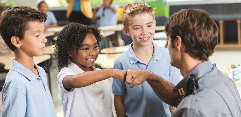 African American student gives policeman a fist bump at school